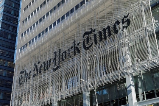 Uitsnede van een hoge glazen gebouw waar The New York Times op staat
